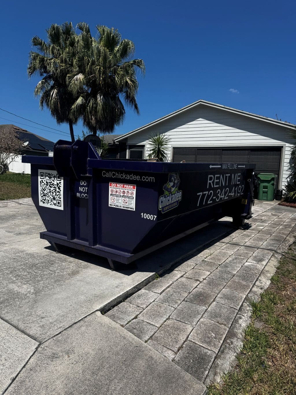 Dumpster rental delivery in Port St. Lucie driveway with protective boards in place