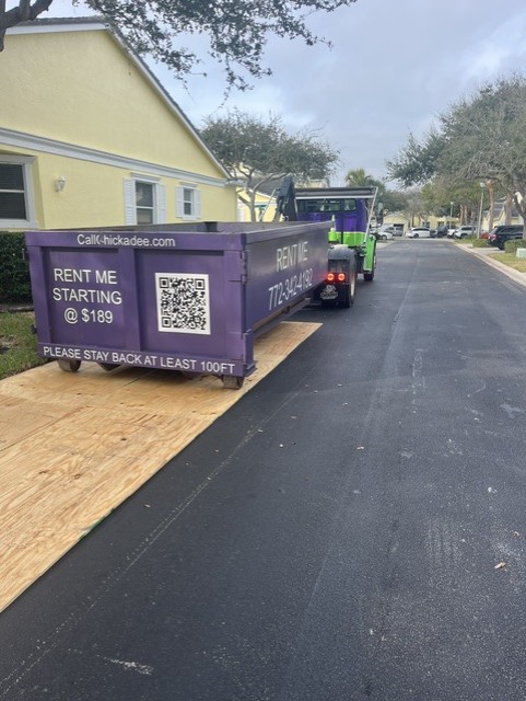 Chickadee placing a dumpster on plywood for a tile roof project in South Beach Fort Pierce FL