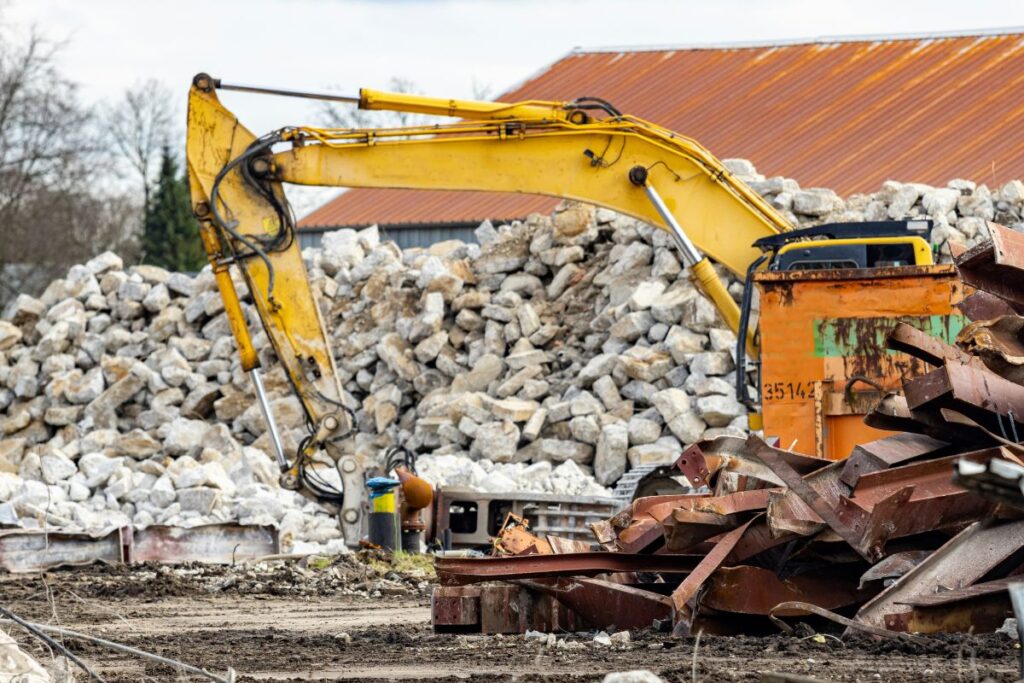 a pile of rubble next to a yellow excavator